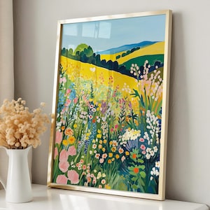 Puede incluir: Una impresión artística enmarcada que representa un campo vibrante de flores silvestres bajo un cielo azul. La obra de arte presenta un marco dorado y una colorida variedad de flores rosas, amarillas y azules. La pintura se exhibe sobre una superficie blanca.