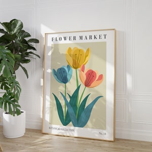 Puede incluir: Un póster de estilo vintage con el texto "FLOWER MARKET" y "BOTANICAL COLLECTION" en un marco dorado. El póster presenta una ilustración colorida de tres tulipanes con hojas verdes sobre un fondo beige claro.