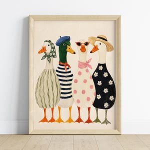 May include: A framed art print featuring four whimsical ducks, each uniquely dressed. One duck wears a striped dress and beret, another a polka-dot dress and sunglasses, and another a floral dress and straw hat. The artwork has a light beige background.