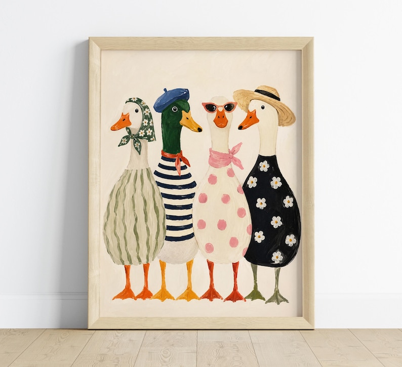 May include: A framed art print featuring four whimsical ducks, each uniquely dressed. One duck wears a striped dress and beret, another a polka-dot dress and sunglasses, and another a floral dress and straw hat. The artwork has a light beige background.