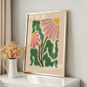 Puede incluir: Una impresión enmarcada con un diseño floral estilizado con flores rosas y amarillas y hojas verdes sobre un fondo beige.