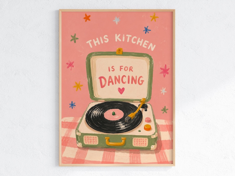 May include: A framed art print featuring a vintage-style record player with the text "THIS KITCHEN IS FOR DANCING" on a pink background. The record player is green and white, with a black record and a yellow tone arm. Colorful star shapes are scattered around the text.