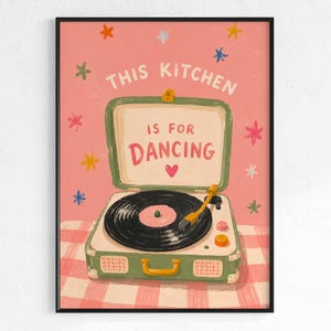 May include: A framed art print with a pink background and the text "THIS KITCHEN IS FOR DANCING." The artwork features a vintage-style record player in green and white, with a black record and a yellow tone arm. Colorful star shapes are scattered around the text.