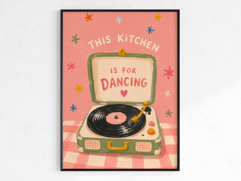 May include: A framed art print with a pink background and the text "THIS KITCHEN IS FOR DANCING." The artwork features a vintage-style record player in green and white, with a black record and a yellow tone arm. Colorful star shapes are scattered around the text.
