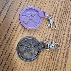 May include: Two keychains with a heart design. One keychain is purple and the other is black.