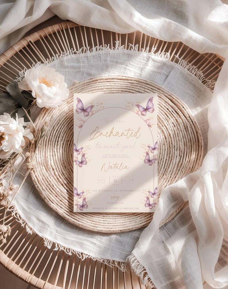 K&ouml;nnte beinhalten: Eine Babyparty-Einladung mit einem Aquarelldesign mit lila Schmetterlingen und floralen Akzenten. Die Einladung lautet "We're Enchanted to meet you!" und enth&auml;lt den Namen "Natalia".