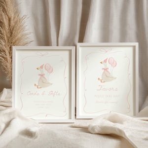 May include: Two framed prints with a light pink goose illustration holding balloons. The text on the left reads "Cards & Gifts", and the right reads "Favors". The frames are white, and the background is a soft, neutral color.
