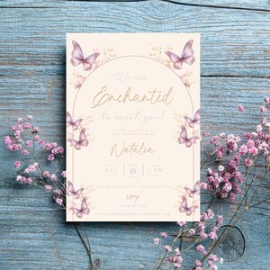 K&ouml;nnte beinhalten: Eine Babyparty-Einladung mit einem Aquarelldesign mit Schmetterlingen und floralen Akzenten. Die Einladung ist f&uuml;r Natalies Babyparty am 10. Mai um 15:00 Uhr. Der Text lautet "Wir sind verzaubert, Sie kennenzulernen!" und enth&auml;lt die Adresse "145 Butterfly Ln, Anywhere City".
