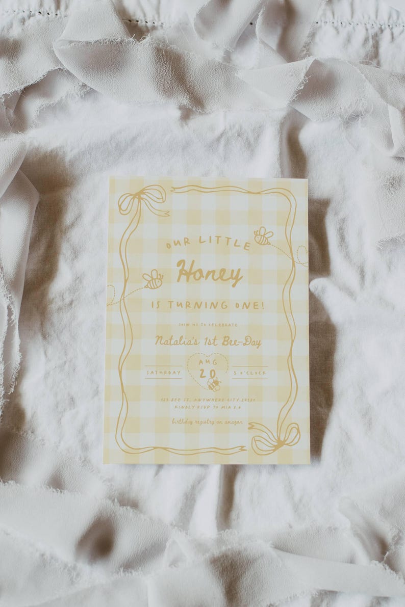 May include: A rectangular birthday invitation card featuring a yellow and white gingham pattern. The text reads Our Little Honey Is Turning One! Natalia's 1st Bee-Day, Aug 20, Saturday, 5 o'clock. It includes illustrations of bees and ribbons.