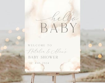 May include: A white welcome sign with a watercolor background in shades of beige and brown. The text reads "hello baby" in a script font and "Welcome to Natalia & Alex's Baby Shower 12 May 2024".