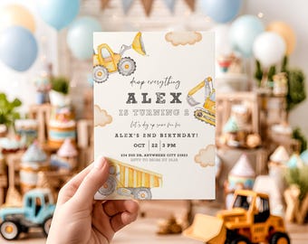 May include: A birthday invitation with illustrations of yellow construction vehicles and the text "ALEX IS TURNING 2." The invitation is held up in front of a party scene with balloons and decorations, suitable for a child's second birthday.