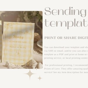 May include: A yellow and white gingham patterned invitation card featuring the text "Our Little Honey is Turning One" with decorative line art borders. The card is displayed alongside a matching blank card, both resting on a white lace fabric surface.