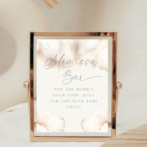 May include: A gold-framed sign with a watercolor background reads "Mom-osa Bar" and includes instructions: "Pop the bubbly, pour some juice and top with some fruit!"