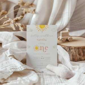 May include: A light blue invitation card with a yellow sun and clouds. The text reads "first trip around the sun Natalia is turning one" and includes the date and time of the event.