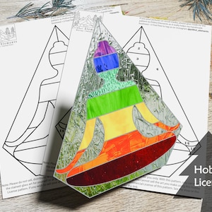 May include: A stained glass pattern of a person sitting in a meditative pose with a rainbow colour scheme. The pattern is printed on a white sheet of paper with the text "Hobby License" printed on the bottom right corner.