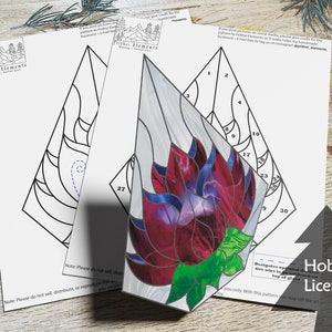 Op de afbeelding: Een glas-in-loodpatroon voor een bloemontwerp. Het patroon is gedrukt op wit papier en bevat genummerde secties voor elk stuk glas. Het patroon is alleen voor een hobbylicentie.