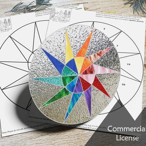 May include: A colourful stained glass suncatcher with a starburst design. The suncatcher is made of glass pieces in shades of red, orange, yellow, green, blue, purple, and pink. The suncatcher is surrounded by a white paper circle with black lines and numbers.