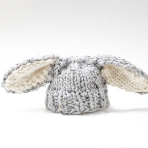 May include: A gray and white knitted bunny hat with long floppy ears.