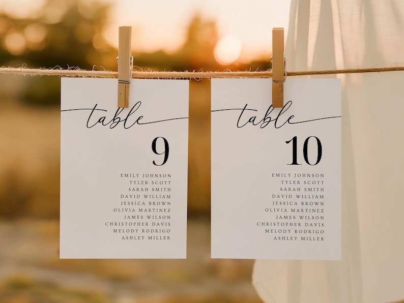 May include: Two white table number cards, labeled "table 9" and "table 10", are suspended by wooden clothespins. Each card features a list of names below the number, with a blurred background.