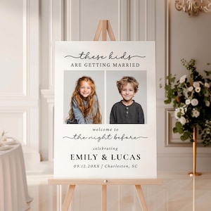 Op de afbeelding: Een wit trouwbord op een houten ezel met de tekst "these kids are getting married". Twee foto's van kinderen staan in het midden. Daaronder staat de tekst "welcome to the night before" en namen en datum.