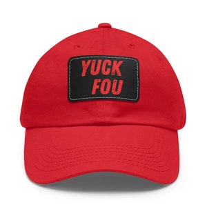 May include: Red baseball cap with a black patch that says "YUCK FOU" in red letters.