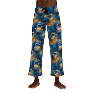 Könnte beinhalten: Blau-orangefarbene Schlafanzughose mit einem Hundegesichtmuster im Aquarellstil. Die Hose hat einen Kordelzug in der Taille und eine lockere Passform. Die Hundegesichter sind in Blau-, Orange- und Gelbtönen gehalten.