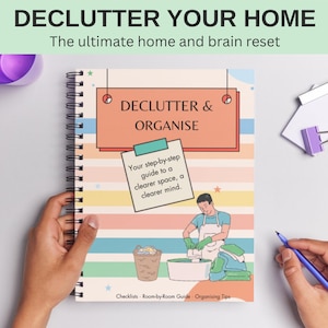Può includere: Un libro a spirale intitolato "DECLUTTER & ORGANISE" con il testo "DECLUTTER YOUR HOME" in alto. La copertina presenta un'illustrazione di una guida passo passo e il testo "Your step-by-step guide to a clearer space, a clearer mind."