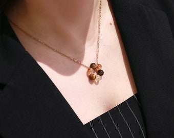 May include: A gold chain necklace with a circular pendant made of brown, gold, and clear beads.