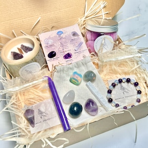 May include: A purple and white crystal gift box with a variety of crystals, a candle, and a bracelet. The box is filled with wood shavings and has a label that says "Mooliit Perception".