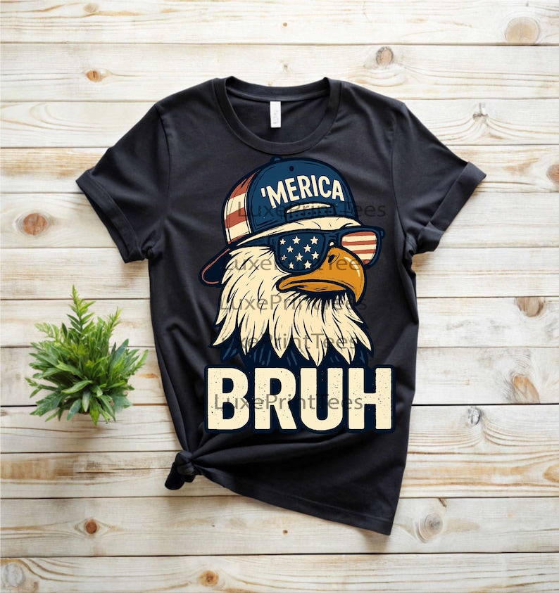 以下が含まれることがあります： サングラスと「'MERICA」の文字が入った帽子をかぶったワシのグラフィックが特徴の黒いTシャツ。「BRUH」の文字が太字で下にプリントされています。