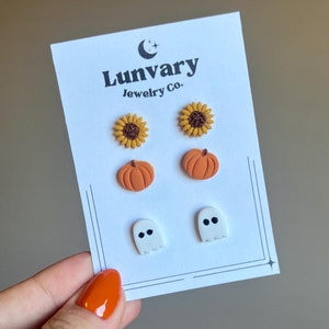 Könnte beinhalten: Ein Set mit sechs kleinen, bunten Ohrringen mit einem Sonnenblumen-, Kürbis- und Geisterdesign. Die Ohrringe werden auf einer weißen Karte mit dem Text "Lunvary Jewelry Co." präsentiert.