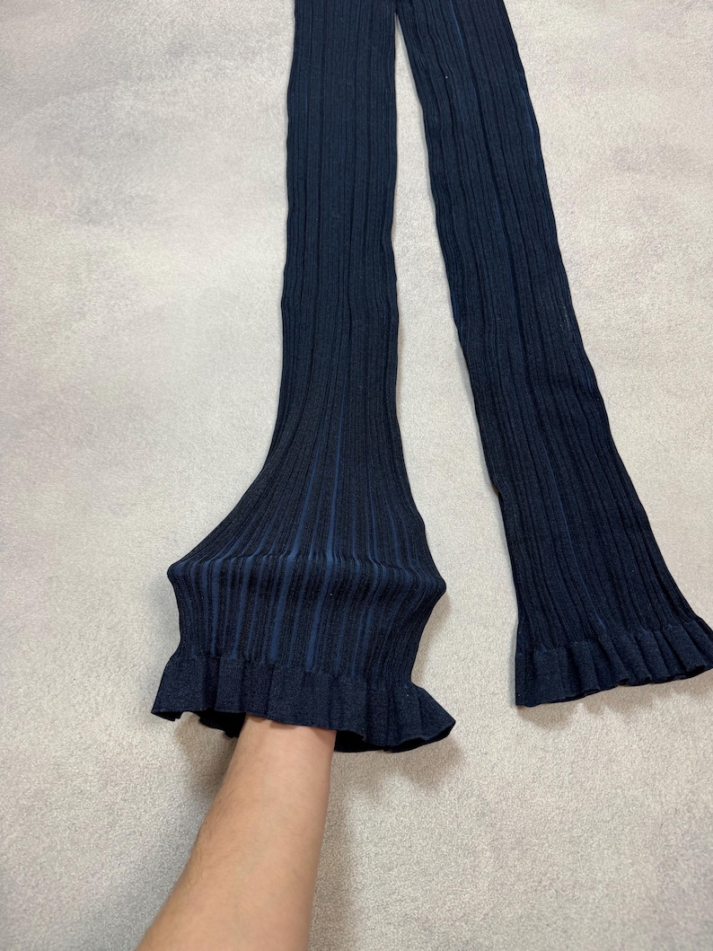 Puede incluir: Calentadores de piernas de punto acanalado azul marino con un volante acampanado en la parte inferior. Los calentadores de piernas est&aacute;n hechos de un material suave y el&aacute;stico y est&aacute;n dise&ntilde;ados para usarse sobre las piernas.