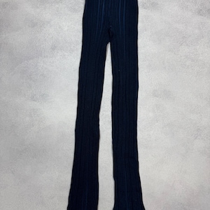 Puede incluir: Pantalones de punto acanalado azul marino con dobladillo con volantes. Los pantalones tienen un dise&ntilde;o acanalado vertical y una silueta ajustada. La tela parece ser un material de punto suave.