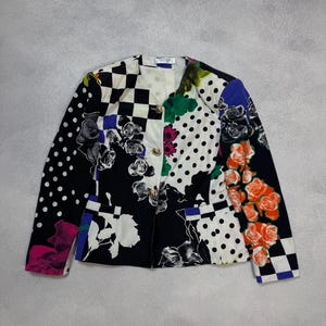 Puede incluir: Una blazer colorida con un diseño de patchwork. La chaqueta presenta una mezcla de patrones, incluyendo lunares, estampados florales y cuadros. La paleta de colores incluye negro, blanco, rosa, naranja y azul.