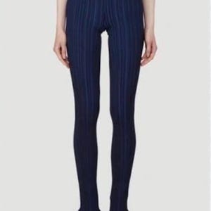 Puede incluir: Leggings azul marino con rayas verticales, cintura alta y dobladillos con volantes. Los leggings son ajustados y parecen estar hechos de una tela acanalada. El modelo lleva zapatos negros.