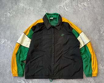 May include: Black Nike jacket with green, yellow, and white color block sleeves and collar. The jacket has a button-up front, two pockets, and a small Nike logo on the chest.