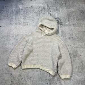 May include: A light gray hooded sweater with a drawstring. The sweater has long sleeves and a ribbed knit texture. The cuffs and hem are a lighter shade of gray. The tag reads "sezane".