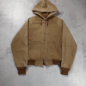 Può includere: Giacca con cappuccio color marrone chiaro con chiusura a zip completa, due tasche frontali e polsini e orlo a coste marroni. La giacca ha un cappuccio con coulisse e mostra segni di usura.