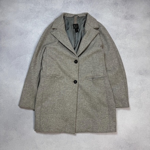 May include: A light gray coat with a notched collar and two black buttons. The coat has two front pockets and a gray interior lining. The coat is made of a textured fabric and has long sleeves.