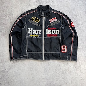 Puede incluir: Chaqueta de carreras negra con costuras blancas, detalles rojos y blancos y múltiples parches bordados. La chaqueta presenta el texto "Harrison Gibson" y el número "9".