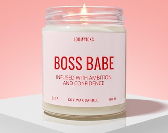 May include: A clear glass jar candle with a white label featuring the text LOOMWICKS, BOSS BABE, INFUSED WITH AMBITION AND CONFIDENCE, 9 OZ, SOY WAX CANDLE, and 60 H. The candle has a lit wick and contains white wax inside the glass container.