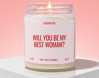 Peut inclure: Une bougie en cire de soja dans un pot en verre transparent avec une étiquette blanche portant le texte rouge LOOMWICKS et WILL YOU BE MY BEST WOMAN? L'étiquette indique également 9 OZ et 60 H. La bougie a une mèche allumée et de la cire blanche.