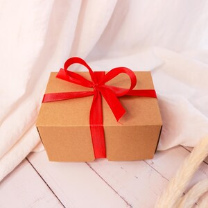 a brown box with a red ribbon on a white table