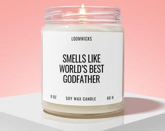 May include: A clear glass jar soy wax candle with a white label featuring the black text LOOMWICKS, SMELLS LIKE WORLD'S BEST GODFATHER, 9 OZ, and 60 H. The candle has a visible lit wick and is filled with white wax, presented in a simple container.