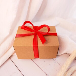 a brown box with a red ribbon on a white table