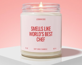 May include: A clear glass jar candle with a white label featuring red text that reads LOOMWICKS, SMELLS LIKE WORLD'S BEST CHEF, 9 OZ, SOY WAX CANDLE, and 60 H. The candle has a visible flame and contains white wax inside the glass container.