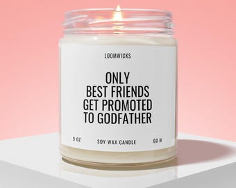 May include: A clear glass jar soy wax candle with a white label featuring the black text LOOMWICKS, ONLY BEST FRIENDS GET PROMOTED TO GODFATHER, 9 OZ, and 60 H. The candle has a lit wick and is filled with off-white wax, emitting a warm glow.