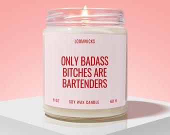 May include: A 255g soy wax candle in a clear glass jar with a lit wick. The white label features the text LOOMWICKS, ONLY BADASS BITCHES ARE BARTENDERS, SOY WAX CANDLE, and 60 H in red lettering against a light pink background.