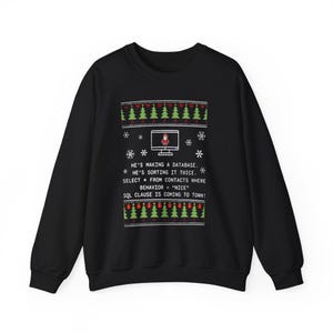 May include: Black sweatshirt with a festive design. The design includes green Christmas trees, red baubles, snowflakes, and text that reads "HE'S MAKING A DATABASE. HE'S SORTING IT TWICE. SELECT FROM CONTACTS WHERE BEHAVIOR = "NICE" SQL CLAUSE IS COMING TO TOWN!"