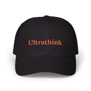 Könnte beinhalten: Schwarze Baseballkappe mit dem Wort "Ultrathink" in Orange auf der Vorderseite gestickt. Die Kappe hat einen gebogenen Schirm und eine strukturierte Passform. Ein klassisches, lässiges Accessoire.